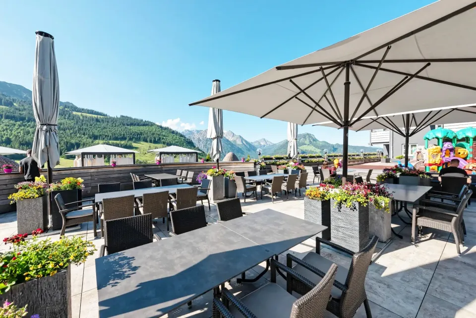 Terrasse mit Großschirmen vor Bergkulisse