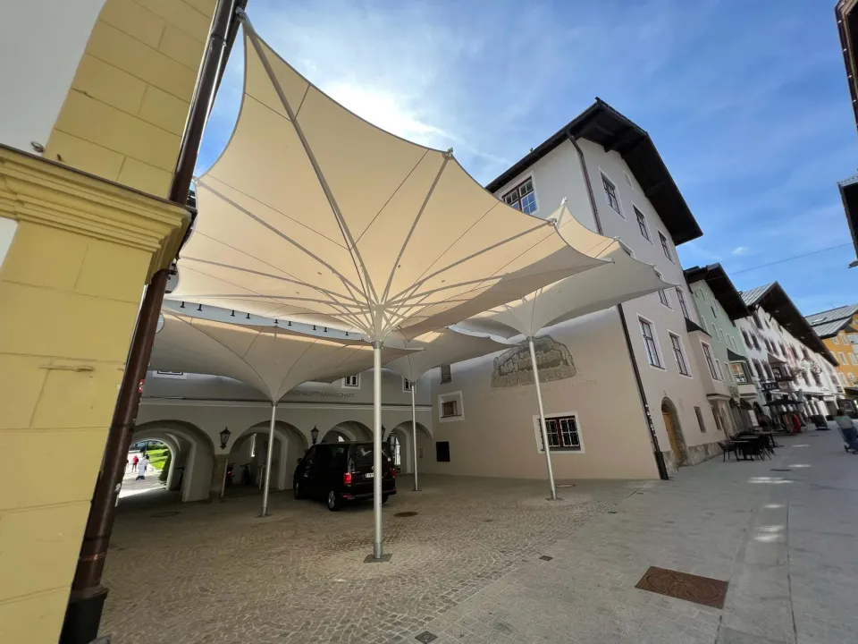 Verfahrbare Trichterschirme 7 × 7 m über einem Innenhof in der Altstadt von Kitzbühel, Fassaden und Arkaden unter den Schirmen