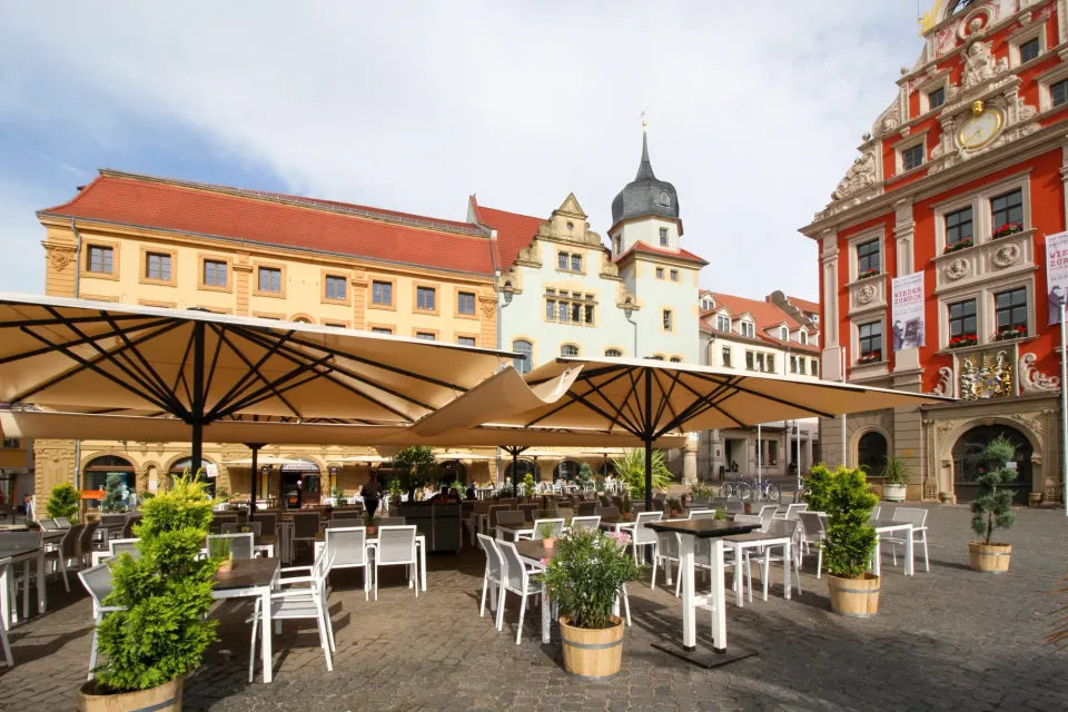 Weiße Großschirme über Tischen auf einem Marktplatz